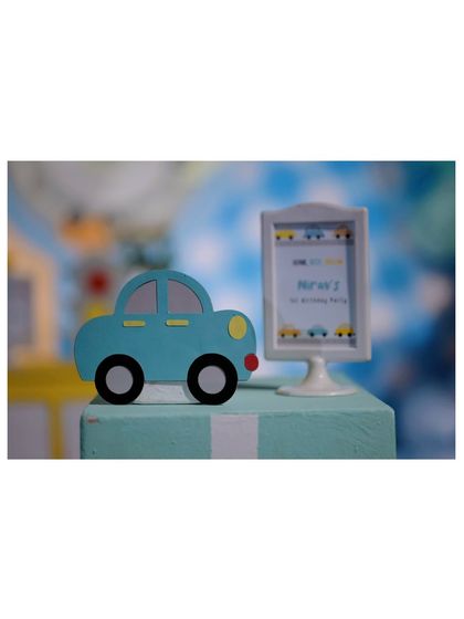 A close-up of a cute blue car prop and a mini-sign for Nirav's first birthday party.