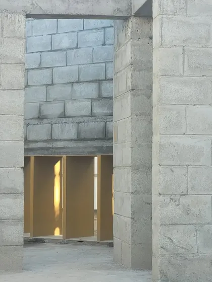 A view through unfinished doorways reveals the layers of the space. The raw concrete block walls give a sense of the building's solid, geometric foundation before the final finishes are applied.