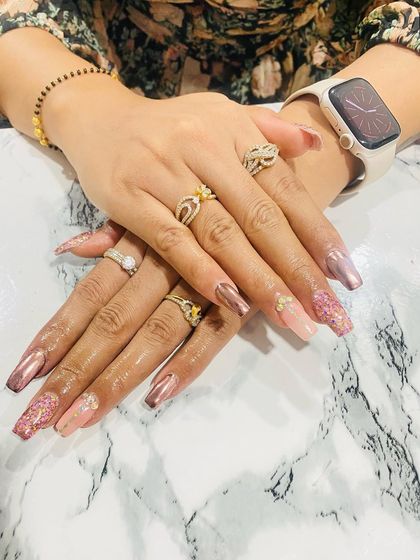This elegant set combines rose gold chrome nails with glitter-encapsulated accent nails. It's a perfect example of how students learn to mix different textures and finishes for a sophisticated look.