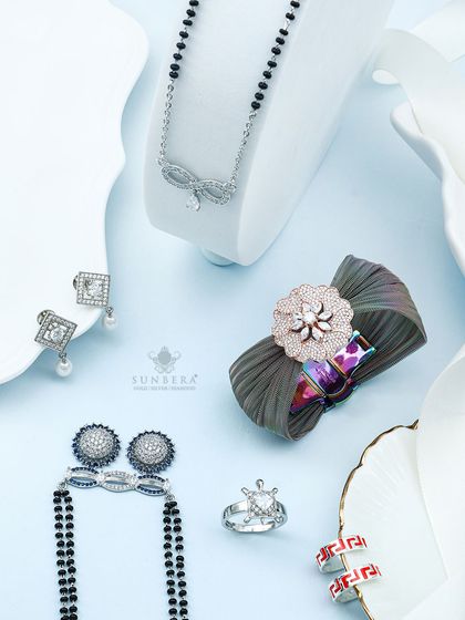 This flat lay showcases the variety in my silver collection. It features a modern mangalsutra with a bow design, square diamond earrings with pearl drops, and a unique fabric scrunchie with a floral diamond centerpiece.