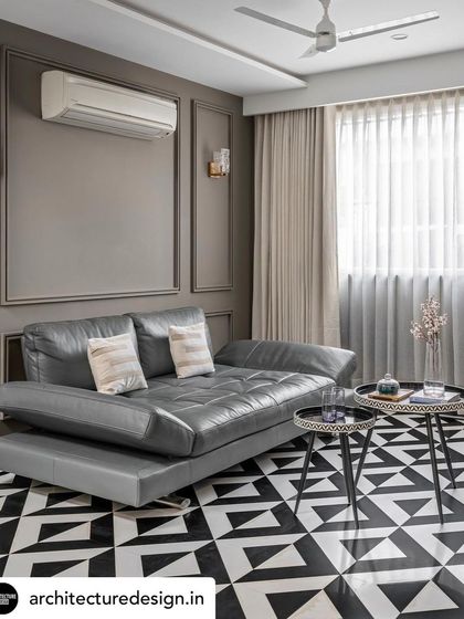 A secondary lounge area showcases a bold geometric-patterned floor in black and white. This graphic element is balanced by serene grey wall paneling and a sleek, modern grey leather sofa.