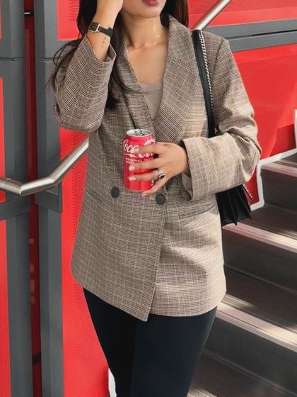 A close-up detail shot of the plaid blazer outfit, focusing on the texture of the jacket and accessories.