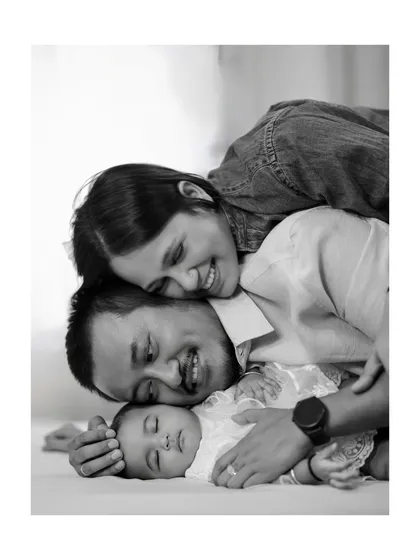 In the quiet moments, love speaks the loudest. This classic black and white portrait captures the profound bond between new parents and their sleeping baby, a memory to hold forever.