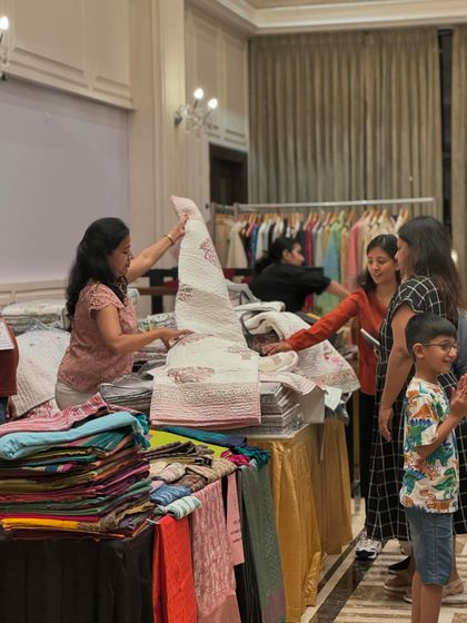 A vendor proudly displays a beautiful quilt to a group of interested ladies. This is where craftsmanship meets its audience.