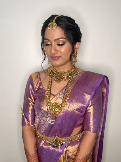 A close-up view of the intricate hairstyle and makeup. The soft curls framing the face add a touch of modern romance to the traditional South Indian bridal look.