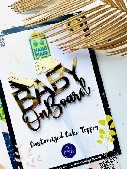 A close-up of the "Baby on Board" topper against its "Hand Made" packaging, emphasizing the personal touch I put into every piece.