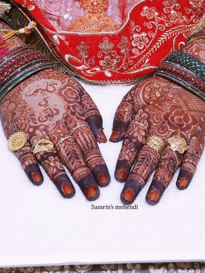 The bride's hands, adorned with rings and a deep henna stain, holding a decorative tray. This is the classic bridal look I love to create.