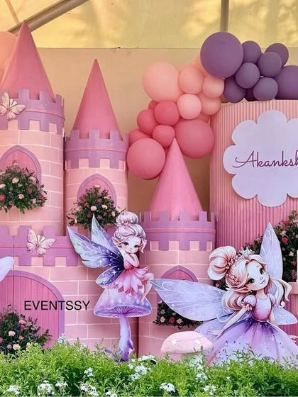 An enchanted fairy wonderland brought to life with a pink castle, whimsical fairy cutouts, and lush greenery.