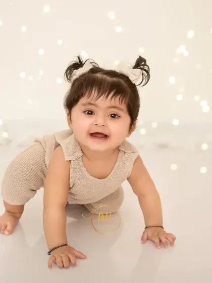 A baby girl in her crawling pose, set against a backdrop of twinkling lights for a magical effect.