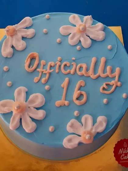 Here's a simple and sweet cake to celebrate a 16th birthday. The light blue frosting is decorated with hand-piped daisies and the message 'Officially 16' in a lovely script.