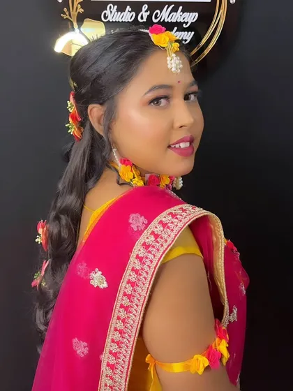 A lovely side profile of a model styled for a Haldi ceremony, showcasing a soft hairstyle with floral details.