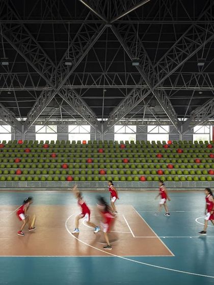 Athletes in motion on the basketball court of the 'Figured Ground' arena. The expansive interior is designed to facilitate a variety of sports, with durable surfaces and excellent lighting creating a professional-grade athletic environment.