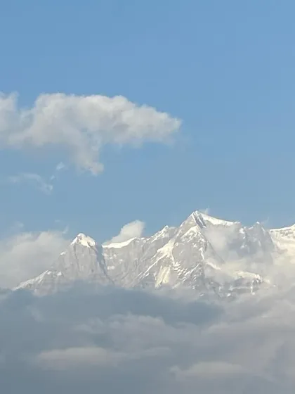 A glimpse of the mighty Himalayan peaks, peeking through the clouds, as seen from the Chopta region.