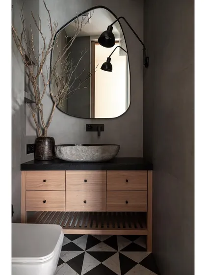 This chic powder bathroom features a black leather-finish marble basin counter that harmonizes with patterned flooring and fabric-finished wall tiles. A generously sized mirror enhances both elegance and the sense of spaciousness.