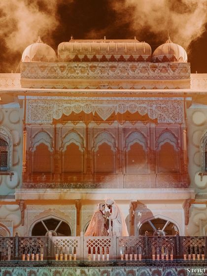 An artistic shot of the couple on the palace balcony, with dramatic orange smoke creating a surreal and powerful image.