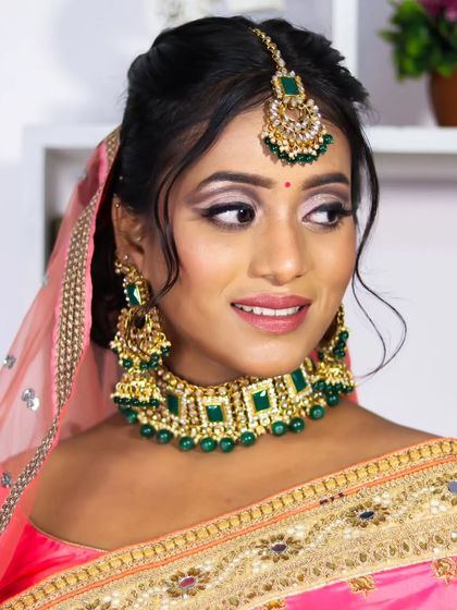 A beautiful close-up of this reception bridal look. The defined, winged eyeliner and emerald green jewelry create a striking and elegant appearance.
