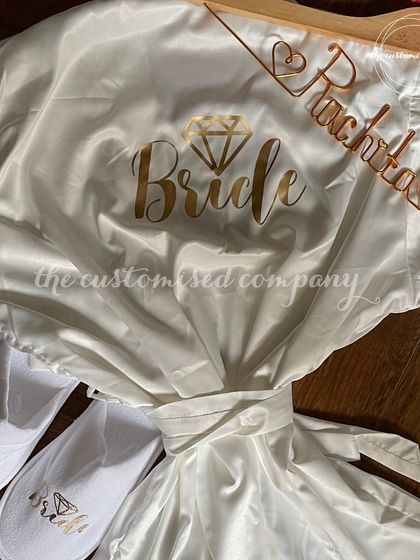 A classic bridal essentials set in white and gold. It includes a personalized satin "Bride" robe, matching slippers, and a custom wire hanger.
