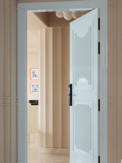 A view through a doorway in Apartment O2, showcasing the light and airy feel of the home. The striped wallpaper and clean lines create a sense of seamless flow between rooms.