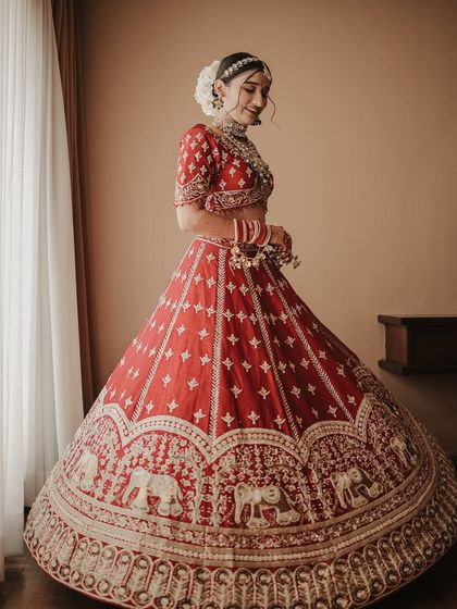A joyful twirl to show off the magnificent lehenga. This shot captures the full glory of her bridal attire, with the elephant motifs on the border, and her happy movement.