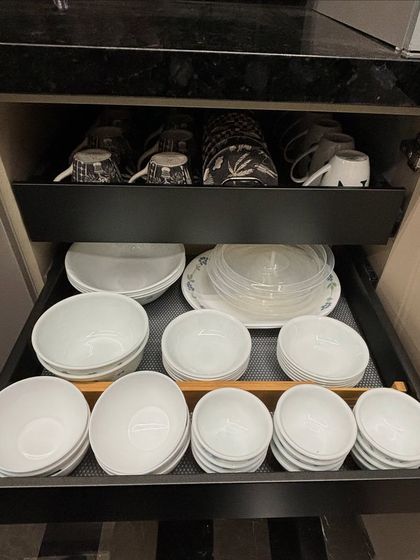 A pull-out drawer system within a cabinet, with zones for cups, bowls, and plates. This is a modern and ergonomic solution for accessing your daily dinnerware.