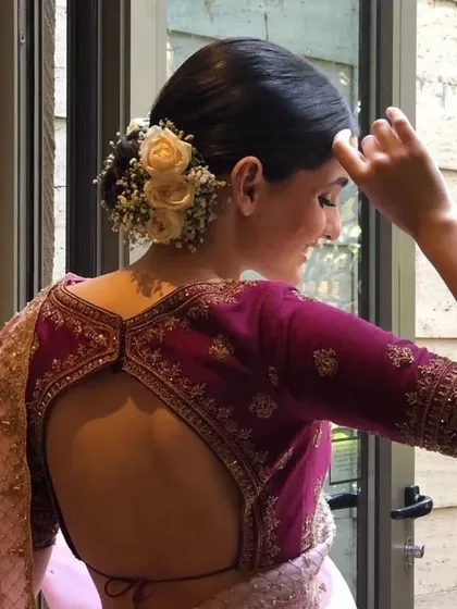 A candid moment of a bride with her hair in a floral bun. This hairstyle is perfect for a romantic and elegant wedding day look.