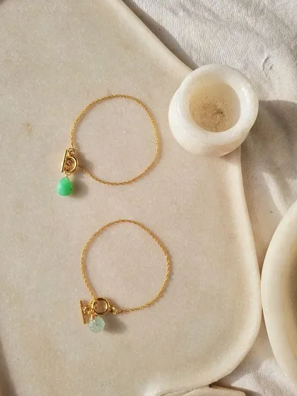 Beyond moonstone, I also work with other healing gems. This image showcases my toggle bracelets, featuring a Chrysoprase initial piece for creativity and an Aquamarine charm for courage and calm.