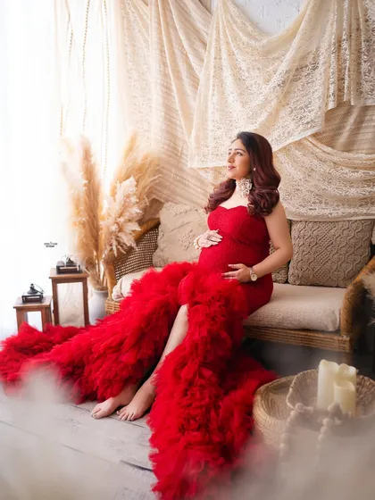 A beautiful shot in our boho setup, this mamma looks radiant in a dramatic red ruffled gown. It shows how we can mix different styles and props.