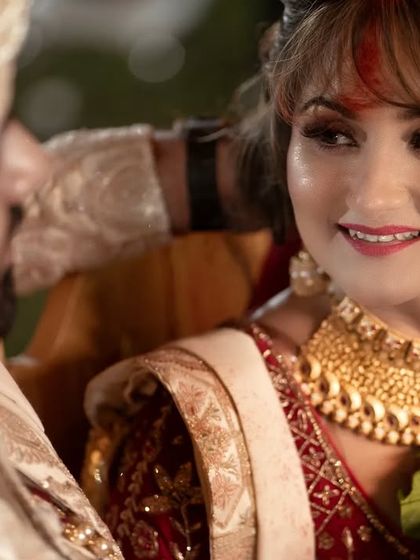 A close-up, intimate moment from a traditional Indian wedding ceremony. The bride's loving gaze at her groom is a perfect candid capture.
