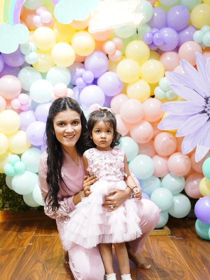 A mother and daughter pose in front of a stunning pastel balloon wall with a butterfly theme, perfect for a magical 2nd birthday.