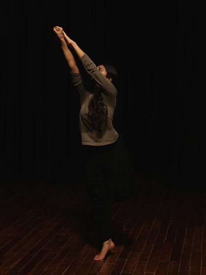 A dancer reaches up during a tech run.