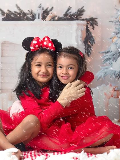 Holiday photos are even more fun with friends. This shot captures two girls sharing a hug in our cozy Christmas fireplace setting.