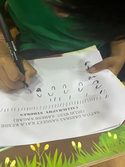 A close-up of a student practicing calligraphy strokes. We provide worksheets to help them master the basic shapes and lines.