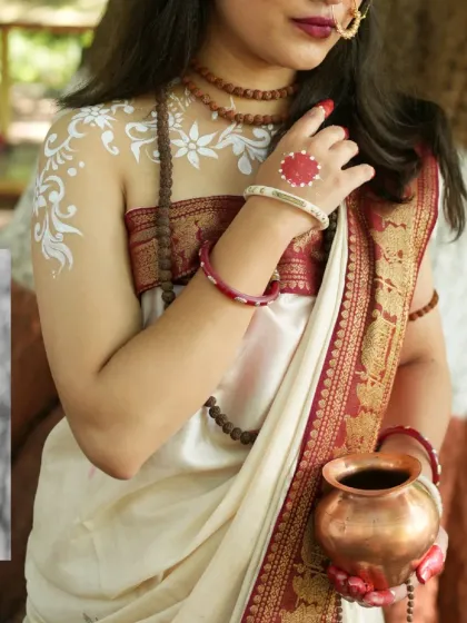A close-up on the details of divinity. This shot highlights the traditional white 'Alpona' body art and the classic red and white saree, central to our Goddess Parvati concept shoot.