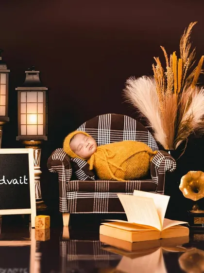 A full view of the elegant "Advait" setup, with the baby's name displayed on a chalkboard. The warm lighting and classic props create a timeless and personalized newborn portrait.