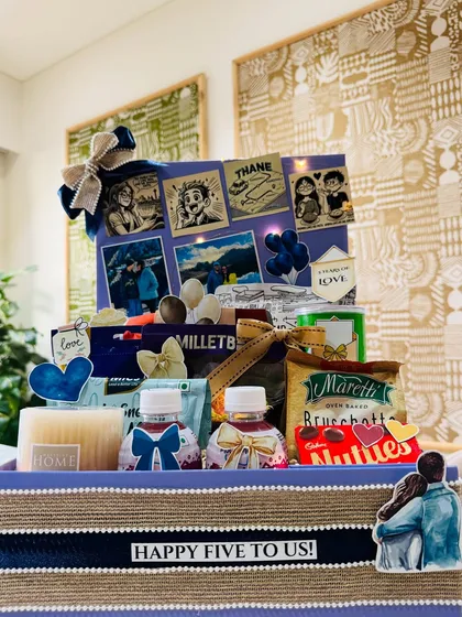 A cute and personal love hamper for a fifth anniversary, featuring a custom collage of their story, from comic-style illustrations to travel photos.
