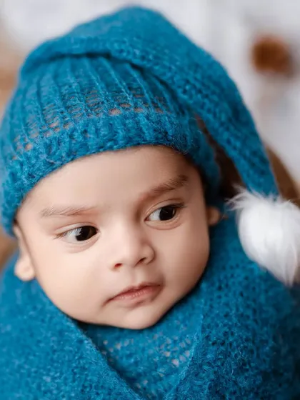 A beautiful close-up of an alert newborn boy. His wide, curious eyes and the cozy blue hat make for an unforgettable portrait.