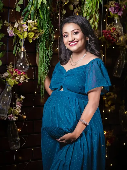 A bright, smiling portrait in the same charming, rustic studio setup. This shot perfectly captures the joy and radiance of the mother-to-be.