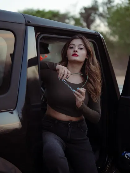 A portrait of a model with a Thar jeep, holding her sunglasses. The outdoor setting and the prop add a story of adventure and attitude to the fashion shoot.