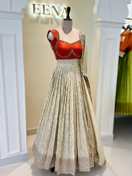 Elegance in every fold. This ivory tissue lehenga with a subtle gold print is paired with a vibrant red katori blouse. The contrast creates a look that is both traditional and incredibly chic.