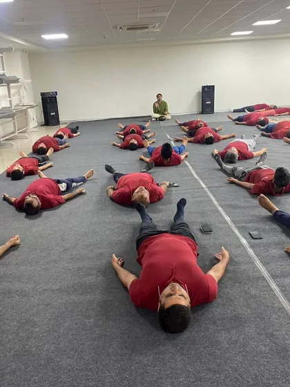 A wide view of a corporate session where employees are in Savasana (Corpse Pose). This final resting pose is crucial for integrating the benefits of the practice, and I ensure there is ample time for it in every session.