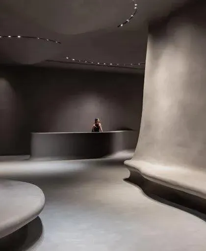 The museum's interior is characterized by flowing, organic forms and minimalist concrete finishes, creating a cave-like, contemplative space.