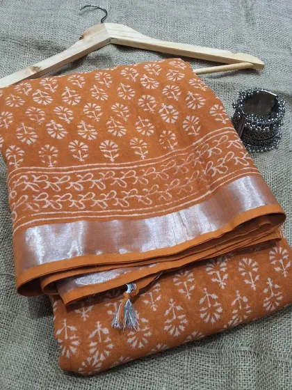 An earthy orange cotton linen saree with a delicate handblock print and a silver border. This saree is lightweight, breathable, and perfect for a stylish yet comfortable summer look.