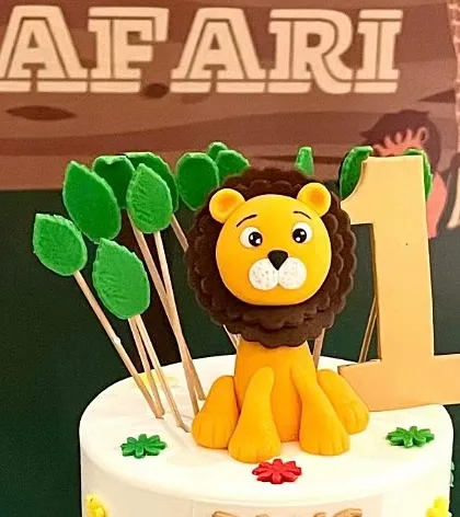 A detailed shot of the jungle-themed cake topper, featuring an adorable fondant lion and the number '1'.