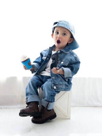 A fun, expressive shot of the toddler in his denim outfit, looking surprised and full of personality.