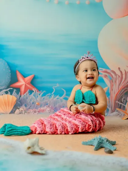 Looking off to the side with a big smile, this photo has a lovely candid feel. The composition beautifully balances the baby with the whimsical underwater scenery.