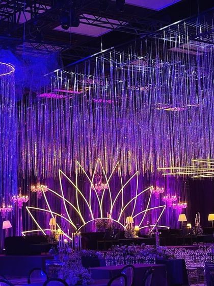 A wide shot showcasing the grandeur of the celestial sangeet hall. The ceiling is covered in thousands of shimmering strings, with large crystal chandeliers creating a sense of a magical, starry downpour over the entire event space.