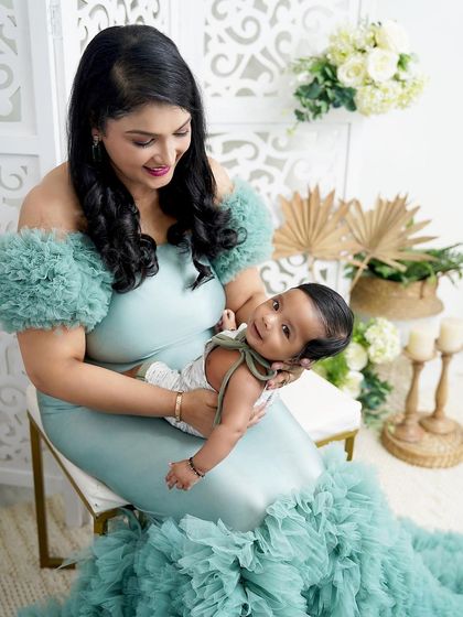 A mother's gentle touch. She cradles her newborn son, whose happy smile is a testament to the comfort and love he feels.