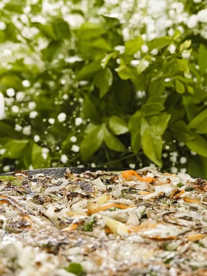 A close-up of our savory Korean pancake, a popular item from our grazing table setups. It's packed with vegetables and flavor, making it a healthy and delicious choice.