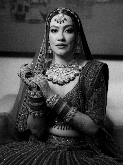 A timeless black and white portrait of a Sikh bride, her hands displaying her chooda and mehendi, her gaze direct and captivating.