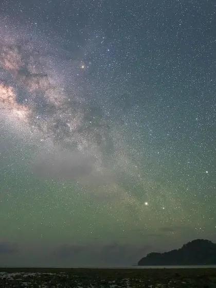 The Milky Way arching over a serene beach in the Andaman Islands. The faint green glow is airglow, a natural phenomenon that adds a magical touch to nightscape photography.